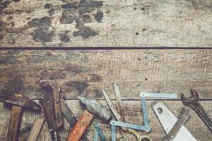 Collection of various hand tools arranged on a rustic wooden workbench in a workshop setting photo