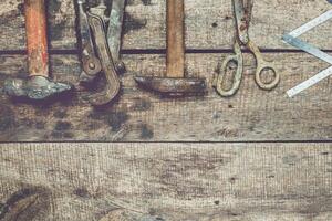 Assorted vintage tools arranged on weathered wooden surface showcasing craftsmanship and history photo