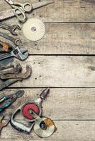 Collection of assorted hand tools arranged on a rustic wooden surface in a workshop setting during daylight photo