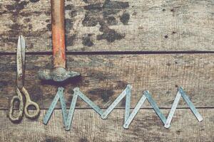 Tools for crafting on a rustic wooden surface with a hammer, scissors, and measuring instruments photo
