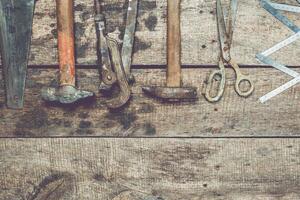 Vintage hand tools arranged on a rustic wooden table in a cozy workshop setting with natural light photo