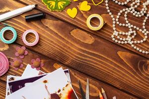 Creative crafting workspace with colorful supplies and printed photographs arranged on wooden table photo