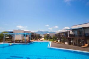 Scenic view of a resort pool area surrounded by modern buildings and mountains on a bright sunny day photo