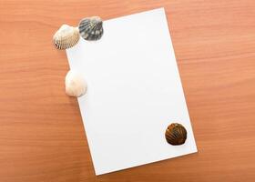Seashells arranged on a blank piece of paper on a wooden surface evoke a serene beach atmosphere photo