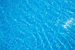 Bright sunlight illuminating clear blue water in a swimming pool during a warm summer afternoon photo