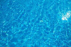 Crystal clear blue water reflecting sunlight in a serene swimming pool setting during the daytime photo