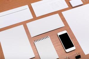 Blank stationery and a smartphone arranged on a wooden desk for creative planning and organization photo