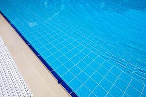 Bright blue swimming pool with tiled edges and sunlit water during a sunny day in a relaxing outdoor setting photo
