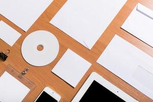 Collection of blank stationery and electronic devices arranged on a wooden workspace for design or planning projects photo