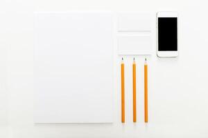 Workspace setup with white paper, orange pencils, and smartphone for creative projects and note-taking photo