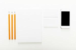 Workspace setup with pencils, blank notepad, business cards, and smartphone on clean surface photo
