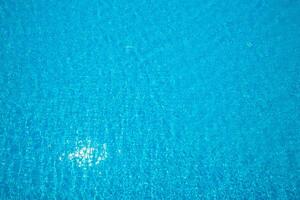 Bright sparkling blue water in a pool reflecting sunlight on a clear day photo