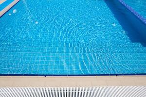 Clear blue swimming pool under bright sunlight inviting relaxation and recreation in a peaceful setting photo