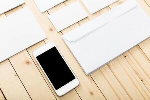 Minimalist workspace setup with blank stationery and mobile phone on wooden surface photo