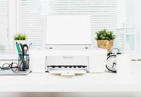 Modern home office setup featuring a printer, desk accessories, and a clock during daytime photo