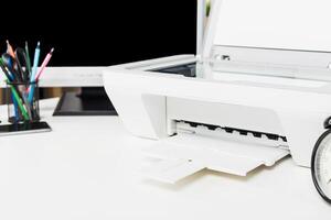 Printer on a desk with stationery and computer, showcasing a workspace setup for productivity and organization photo