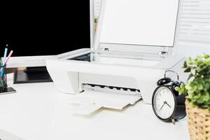 Desk setup features a printer, clock, and plants in a bright workspace promoting productivity and organization photo