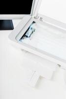 Printer scanner positioned on a modern desk with open lid and paper tray at a bright workspace photo