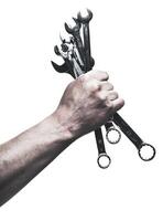 Hand holding multiple tools demonstrating readiness for mechanical work in a workshop setting photo