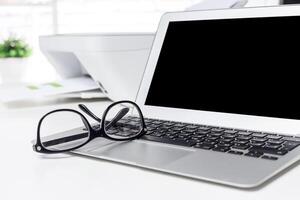 Laptop and glasses on a workspace with a bright background creating a professional atmosphere for productivity photo