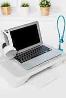 Modern workspace with a laptop, printer, and headset set up for productivity photo