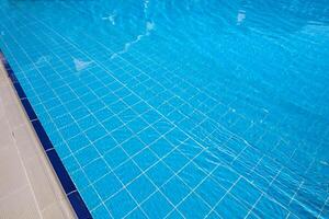 Clear blue swimming pool with tiled edges reflecting sunlight during a warm afternoon photo