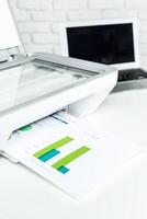 Scanning documents and graphs in a bright office environment with a laptop nearby photo