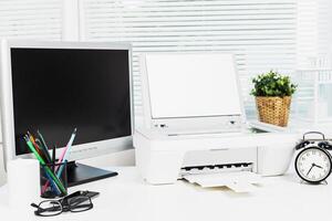 Compact workspace featuring a printer, monitor, and office supplies in a bright and organized environment photo