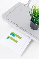 Printer in a modern office with a potted plant and printed graph displayed on the table photo