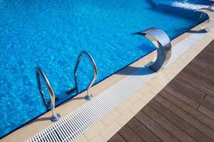 Unique swimming pool design with silver handrails and clear blue water in a modern setting photo