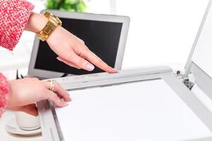 Hands pressing a button on a scanner while preparing documents in a modern office setting photo