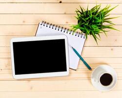 Tablet, notebook, pen, and coffee cup on wooden table creating a productive workspace for studying or working photo