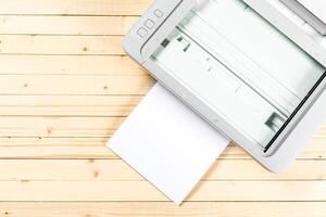 Scanner ready to process white paper against a wooden tabletop in a well-lit workspace photo