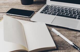 Modern workspace with laptop, smartphone, and open notebook on rustic wood table photo