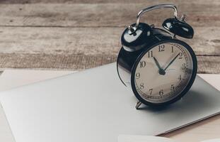 Vintage clock resting on silver laptop in a cozy workspace during afternoon hours photo