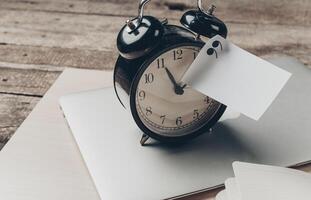 Clock on a laptop with a note attached is a reminder for tasks at a workspace photo