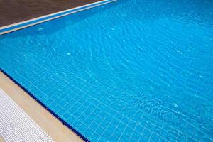 Sparkling blue water glistens under sunlight at a pristine swimming pool in a serene outdoor setting photo