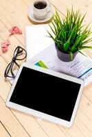 Workspace setup with tablet, documents, coffee, glasses, and plant creating a productive environment photo