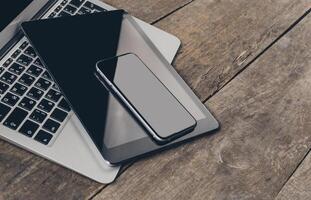 Workspace setup with laptop, tablet, and smartphone on wooden table photo