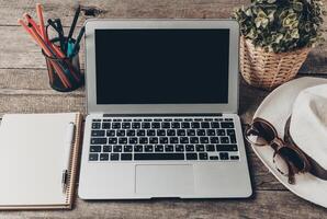 Workspace setup with laptop, notebook, and accessories on wooden table for creative planning and productivity photo