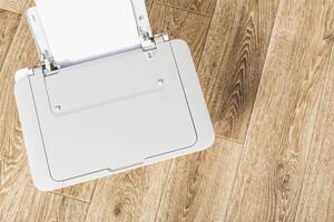 Printer on a wooden floor for home office use with blank paper ready for printing at an afternoon time photo
