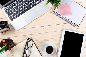 Workspace with laptop, notebook, coffee cup, and tablet on wooden table photo