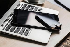 Workstation setup with laptop, tablet, and smartphone on a wooden desk photo