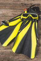Snorkeling gear laid out on wooden surface highlighting vibrant yellow fins and mask in preparation for underwater adventure photo