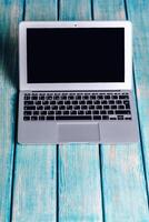 Laptop on blue wooden desk with black screen and minimalistic design highlighting a workspace atmosphere photo