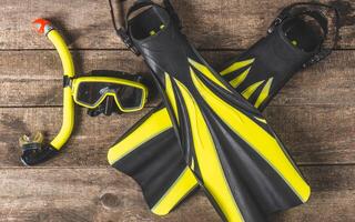 Snorkeling gear arranged on a wooden surface showcases vibrant fins and mask, perfect for underwater adventures photo