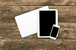 Modern technology devices arranged on wooden surface showcasing a laptop, tablet, and smartphone photo