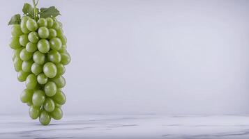 A bunch of fresh green grapes hanging against a minimalist white background, ideal for healthy eating concepts photo