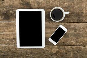 Digital devices and a cup of coffee on a rustic wooden table in a calm workspace setting photo