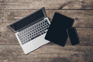 Multiple digital devices arranged on a wooden surface with a natural aesthetic during daylight hours photo